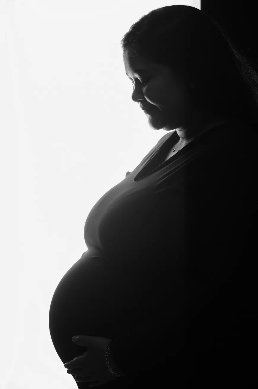 Artistic monochrome portrait of expecting mother in a black gown