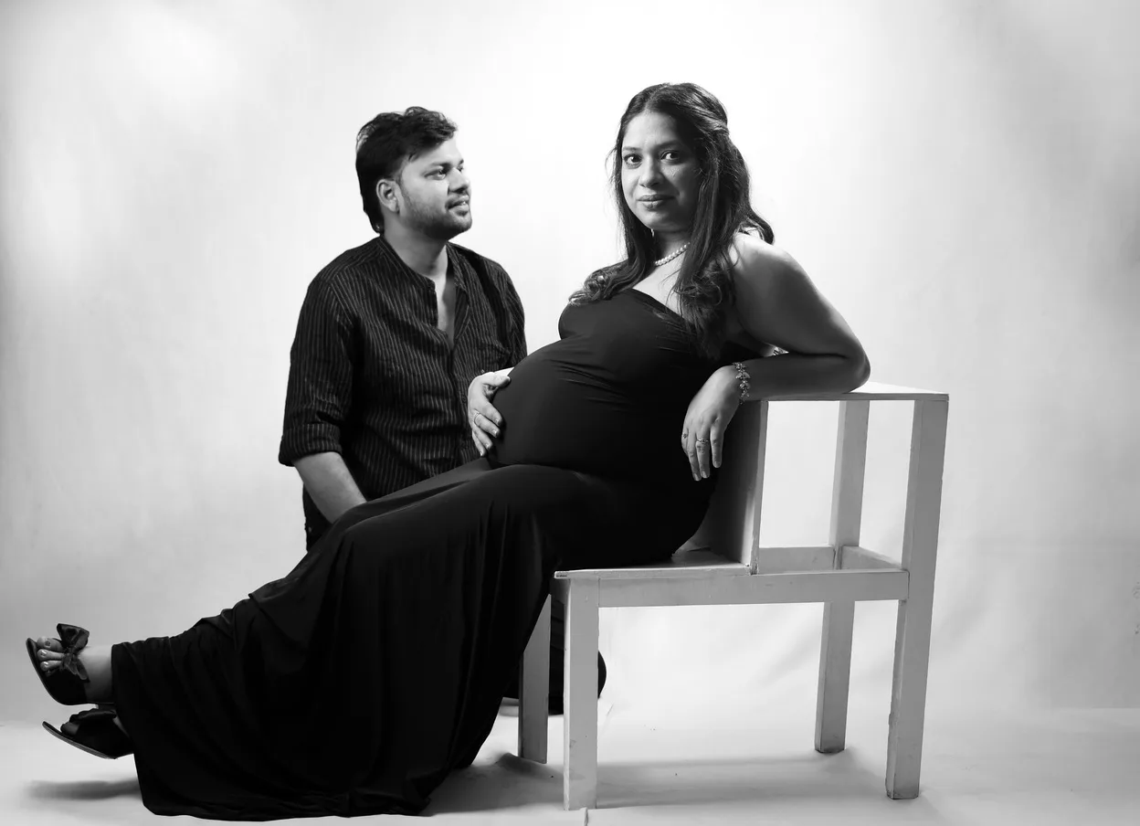 Black and white couple portrait with husband sitting on a chair and wife standing