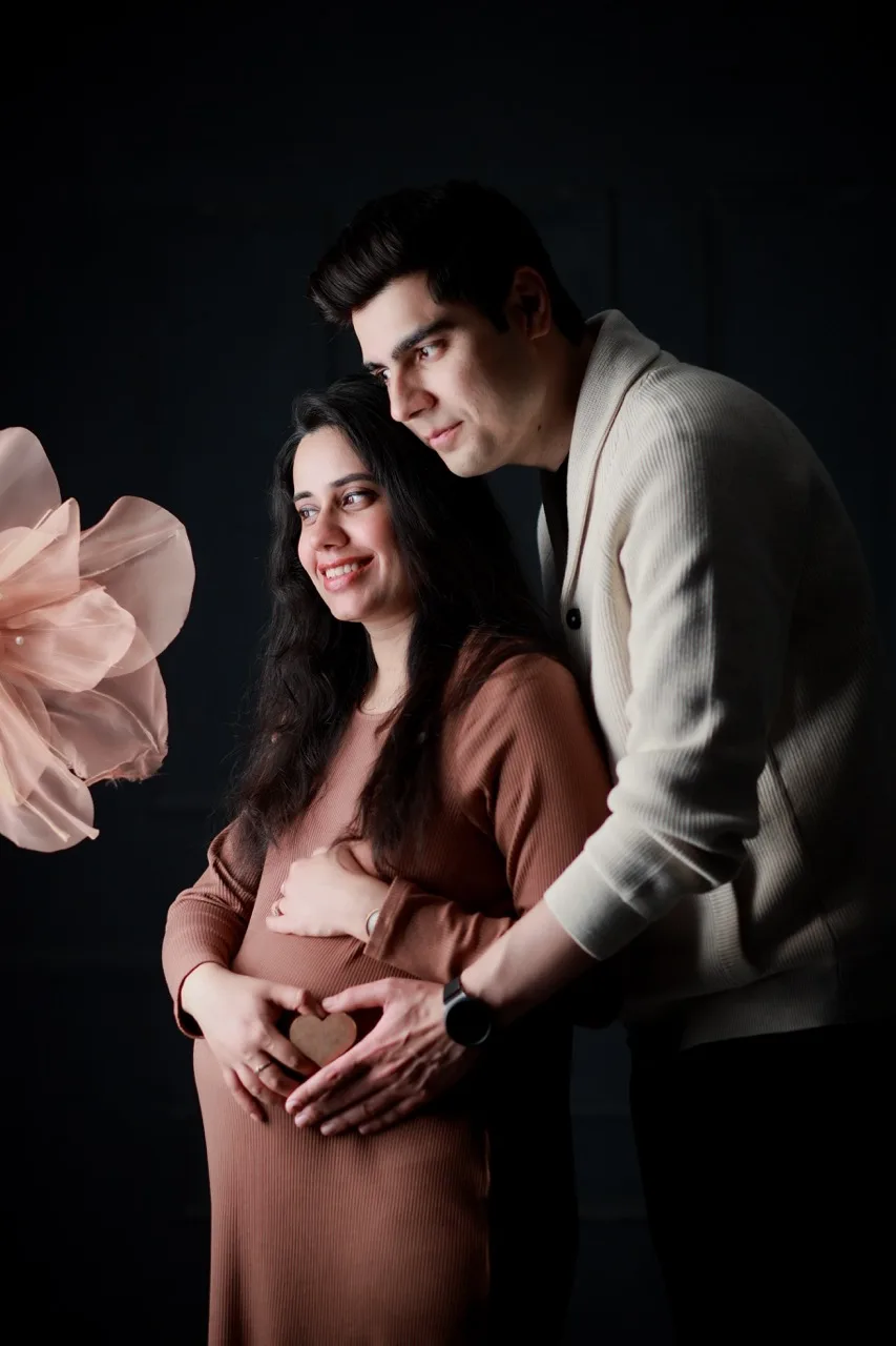 Warm couple portrait with expecting parents posing together in a cozy studio setting