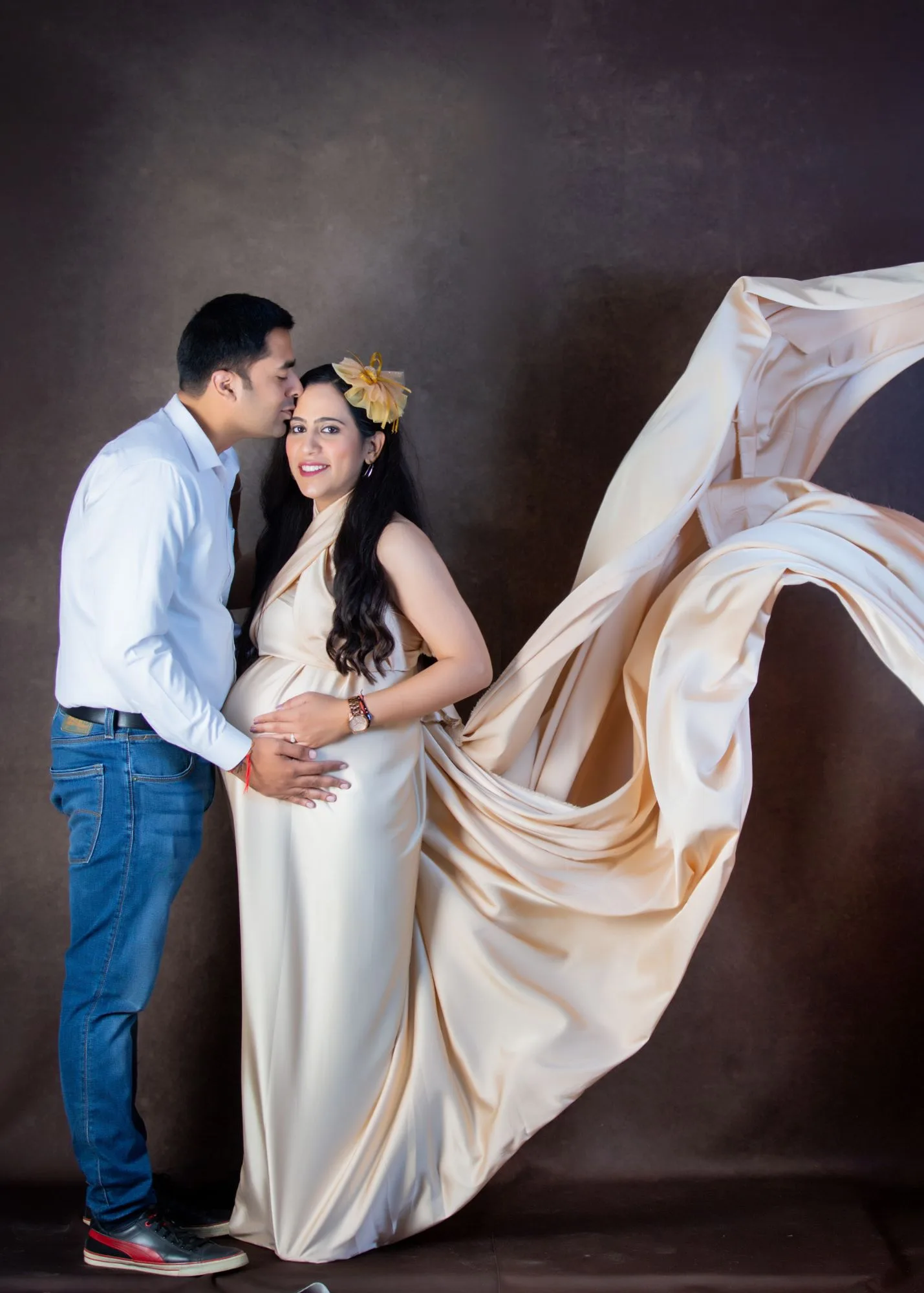 Husband embracing wife from behind during a maternity photoshoot