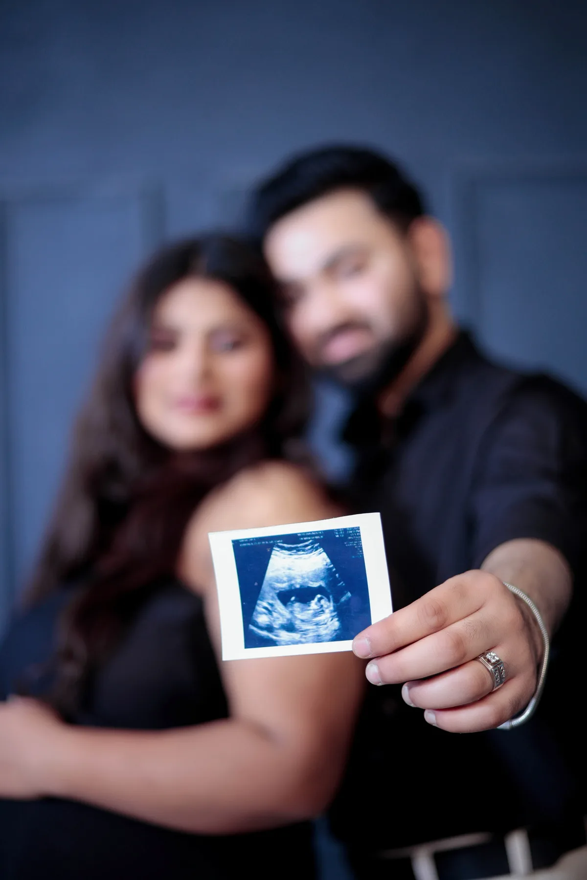 Smiling expectant couple looking at each other during a baby bump session