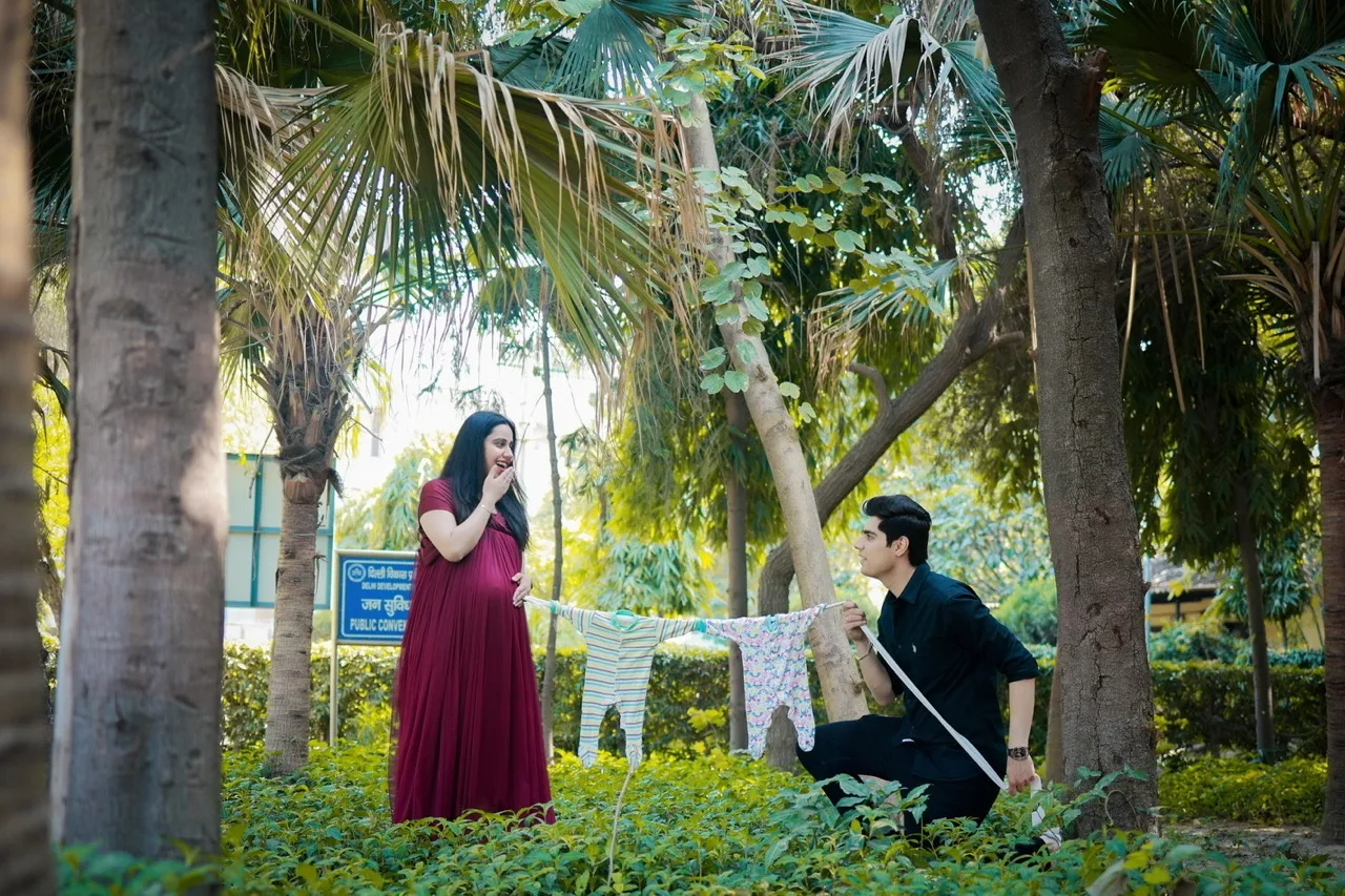 Expectant mother standing in a vibrant maroon maternity gown with a flowing train