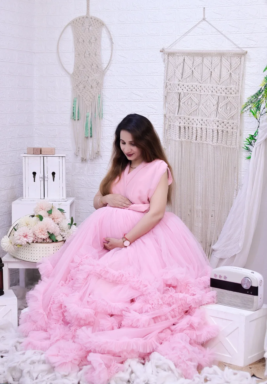 Maternity portrait of expectant mother in a pink dress holding a bouquet of flowers
