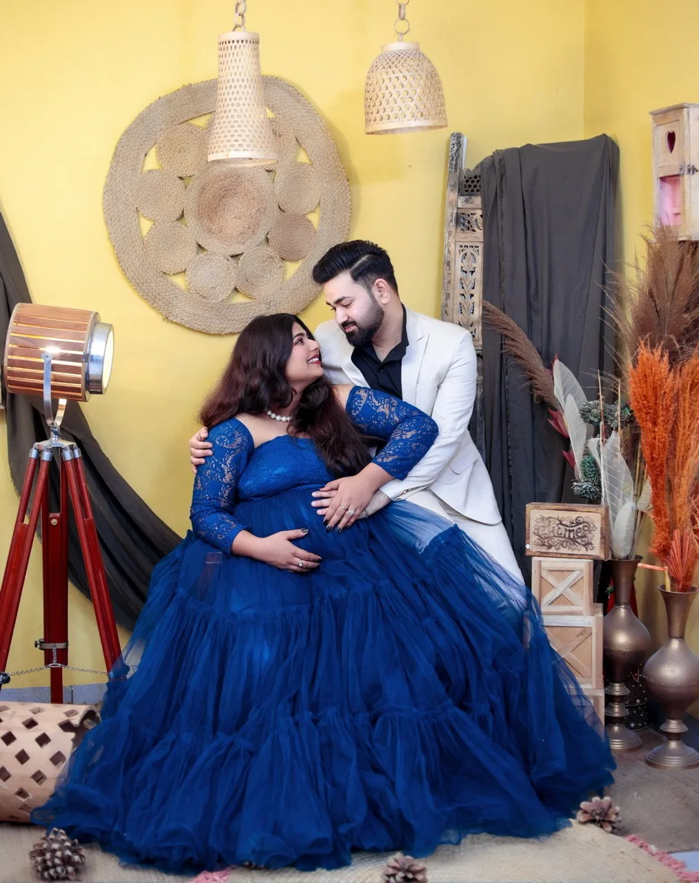 Couple maternity shoot with expecting mother in a blue bohemian dress and husband in a studio theme