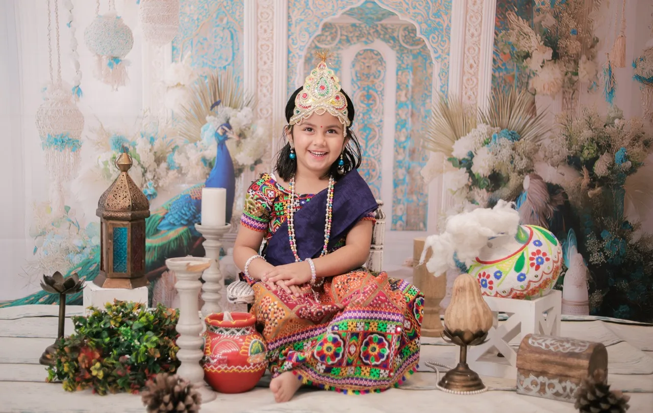 Happy baby girl in a colorful Radha dress for a Darbar theme photoshoot, Janmashtami Krishna theme baby photoshoot in Delhi NCR.
