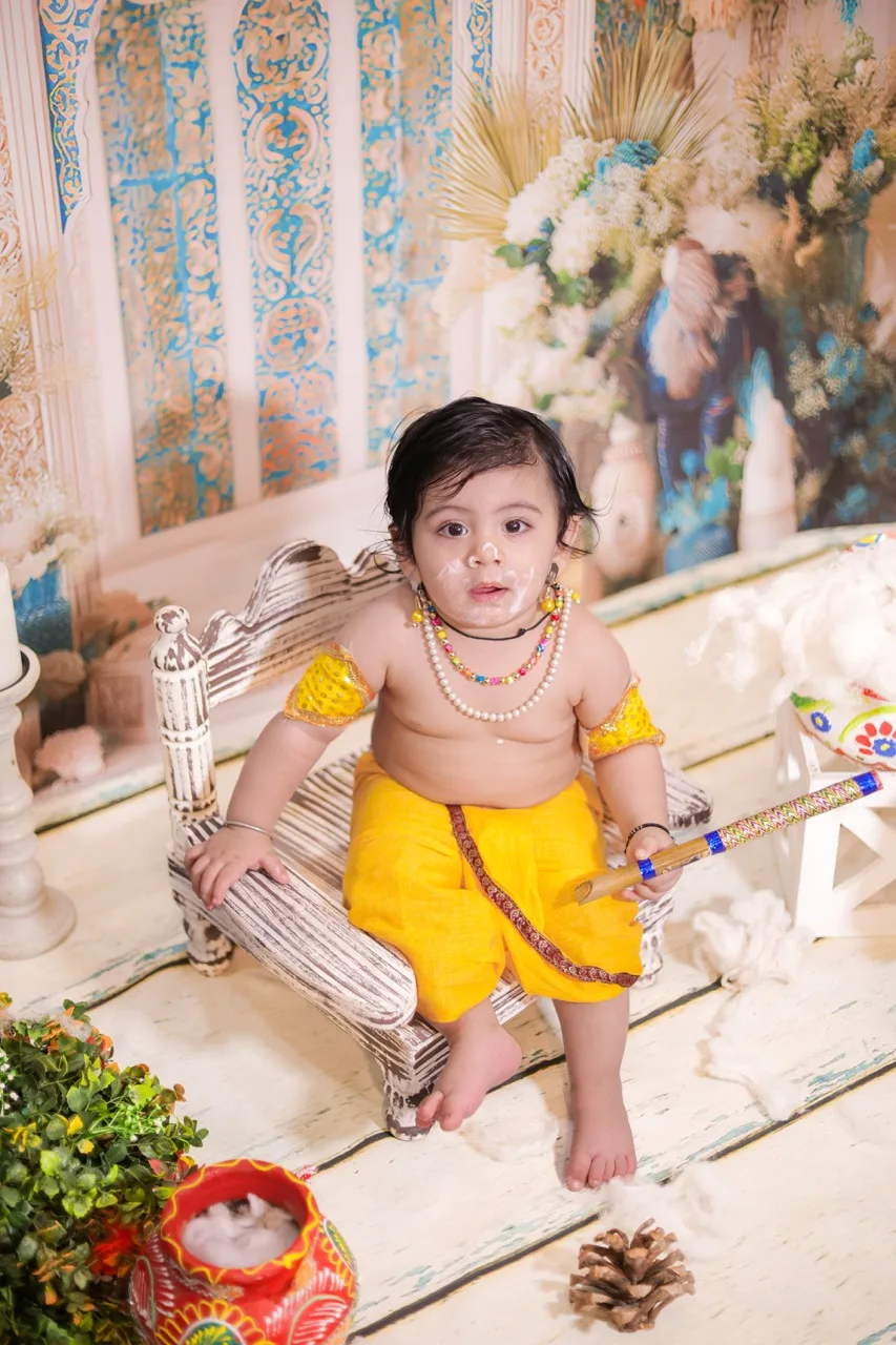 Cute baby boy dressed as little Krishna sitting on a small throne, Janmashtami Krishna theme baby photoshoot in Delhi NCR.