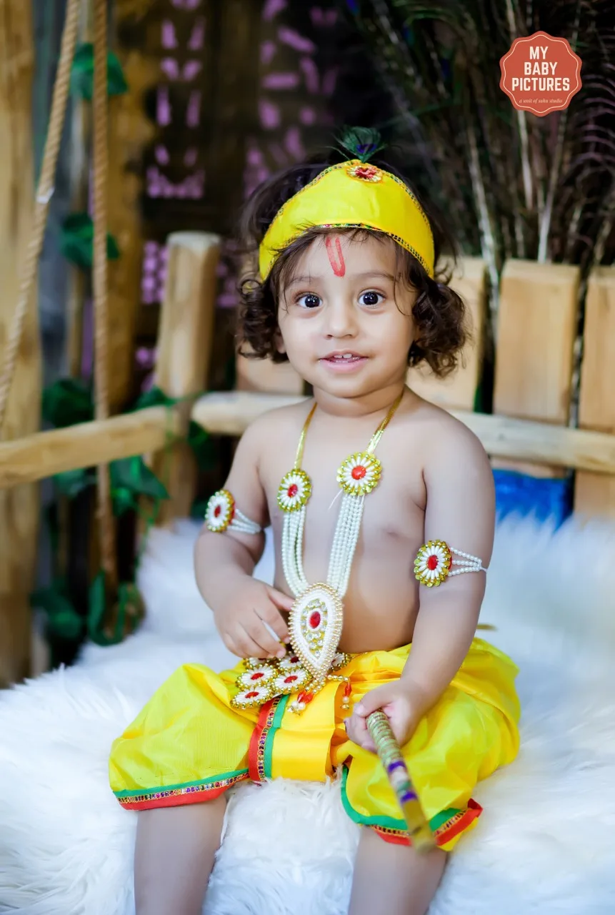 Toddler boy in Krishna outfit sitting on a jhula for a photoshoot, Janmashtami Krishna theme baby photoshoot in Delhi NCR.